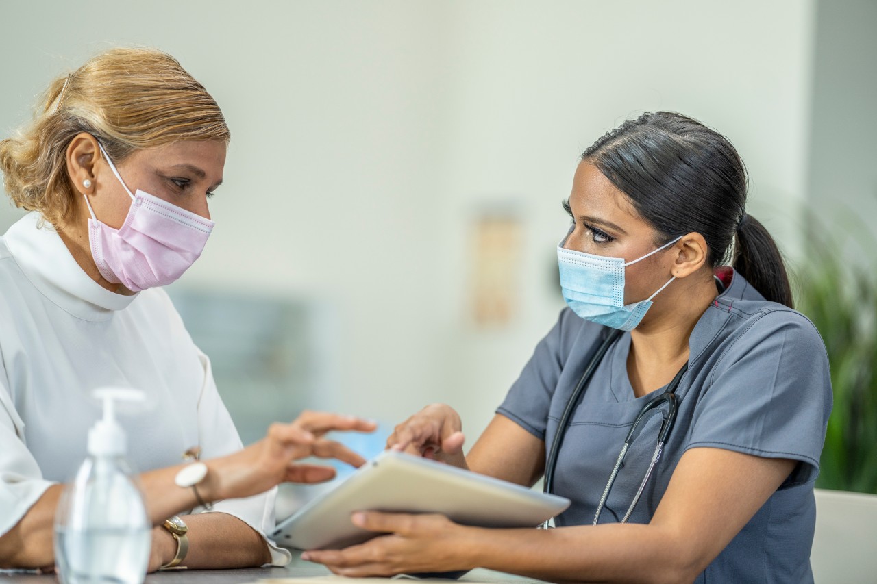 A doctor and patient with masks discuss care