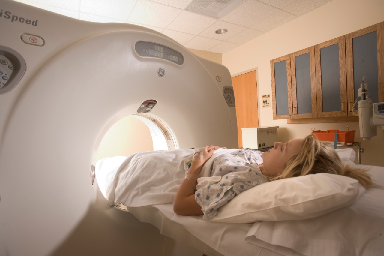 Man operating a CT scaner machine with a female patient getting ready for the procedure